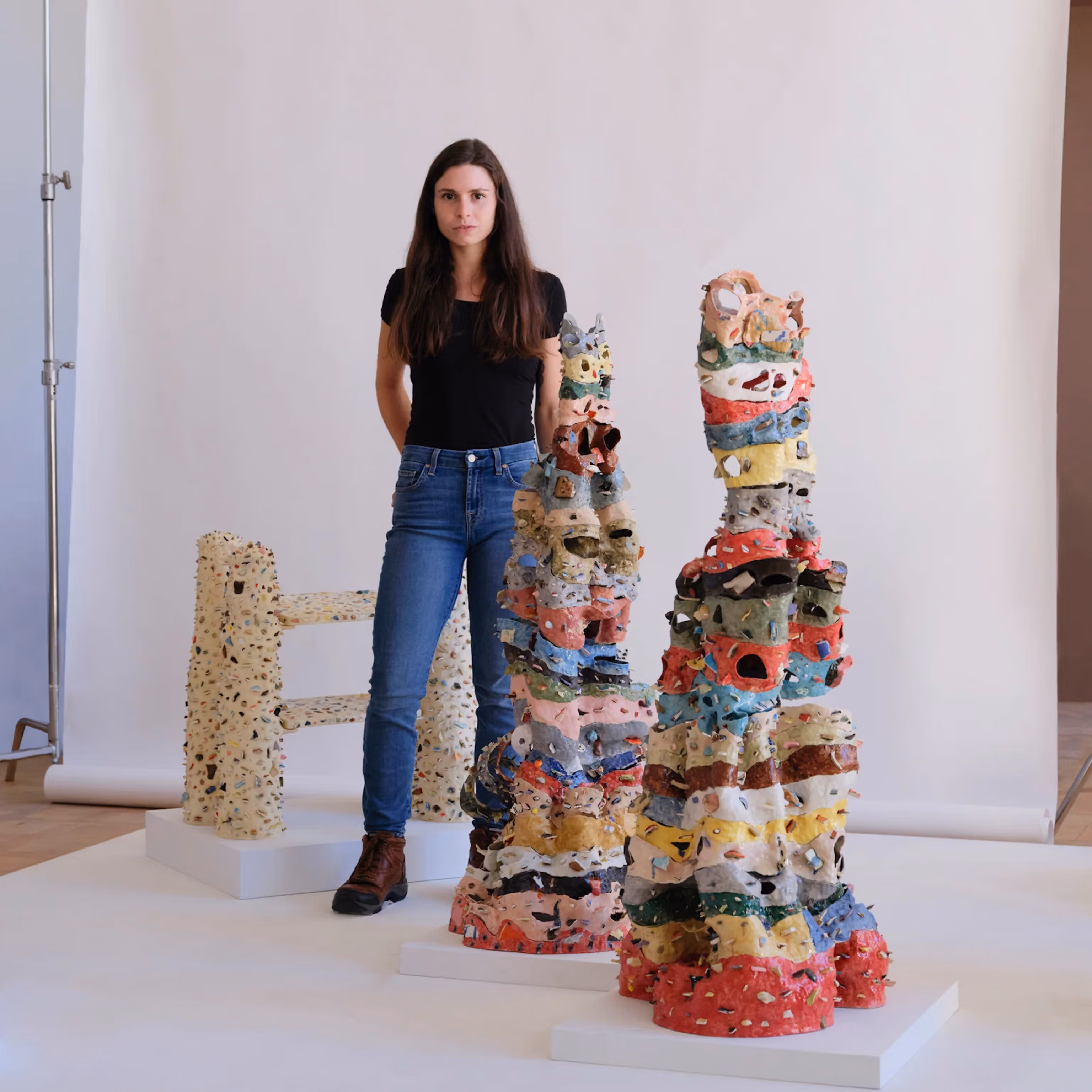 Isabella Maroon standing beside her stacked ceramic sculptures